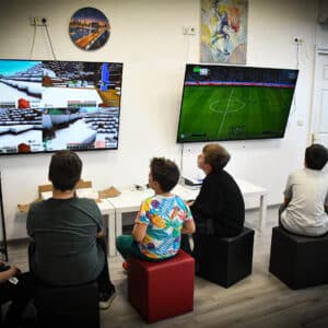 Група деца играят Minecraft и FIFA на големи екрани в гейм зона.