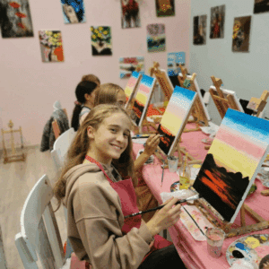 Усмихнато момиче с четка пред платно на статив