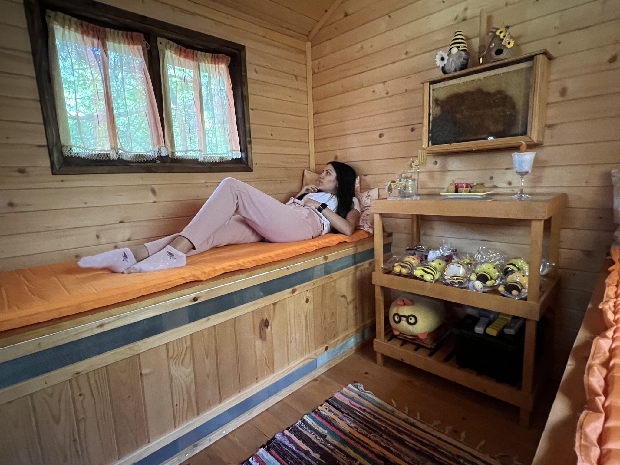 Жена почива на легло в апикъща с дървена облицовка.