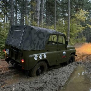 Военен джип заседнал в кална локва сред гъста борова гора